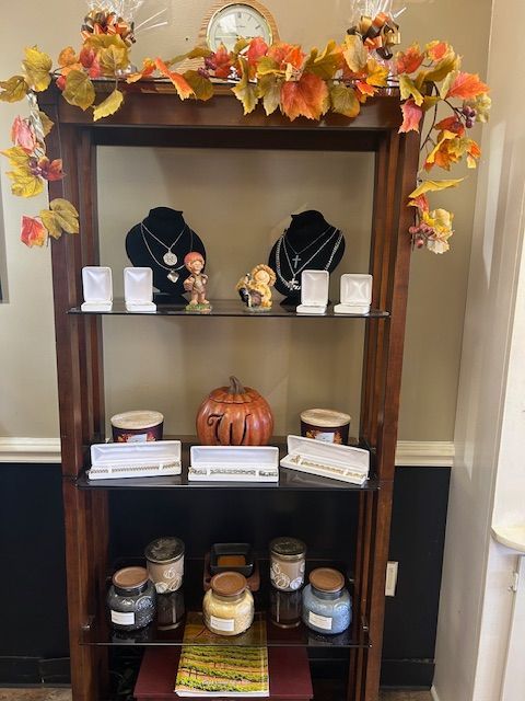 Jewelry display case decorated with fall foliage. Necklaces, candles, and a pumpkin are visible.