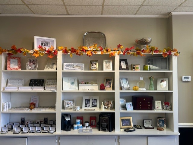 White shelves displaying decorative items, including frames, candles, and garland, in a store.