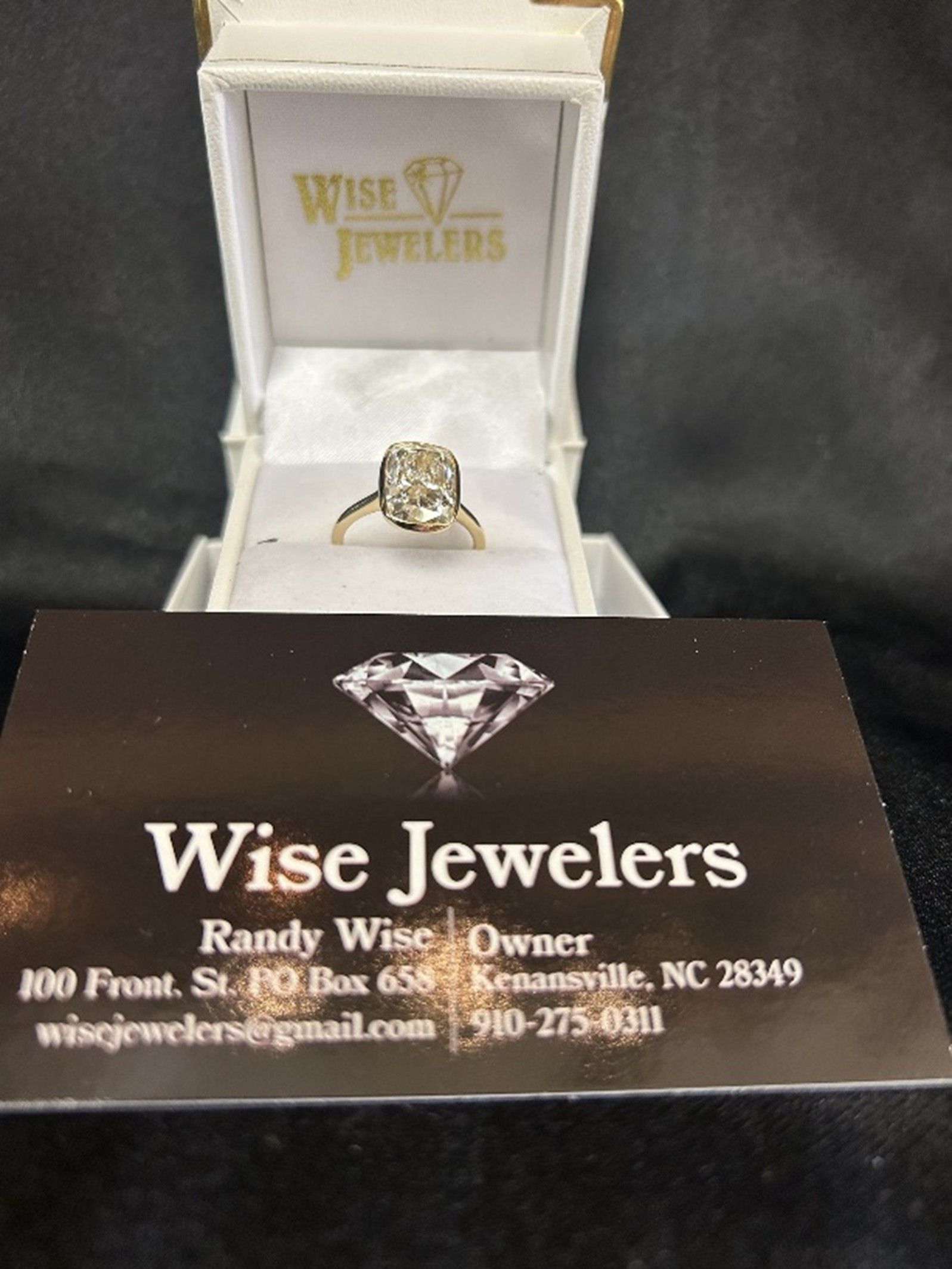 Ring in a box from Wise Jewelers with a business card below.