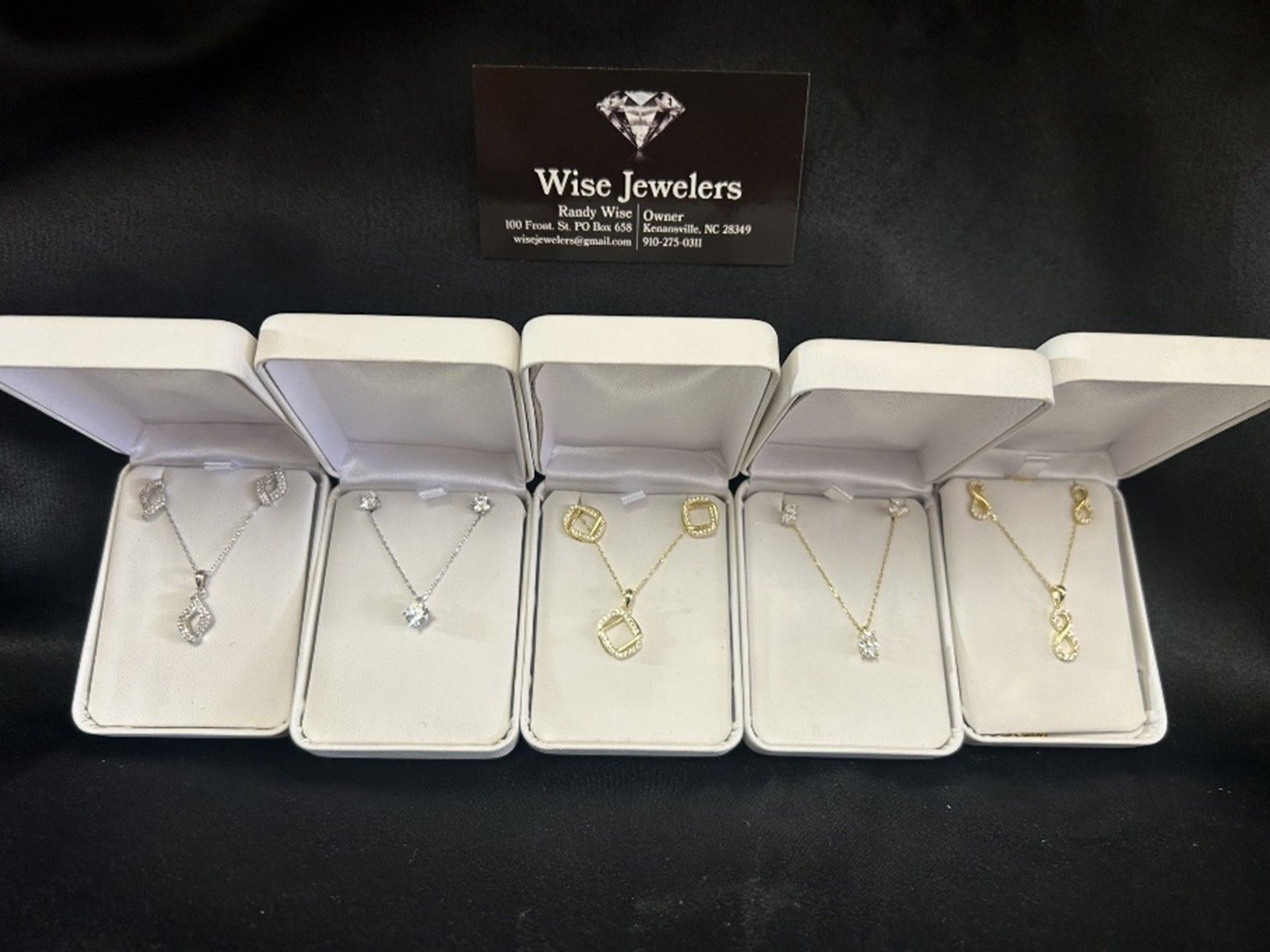 Jewelry in boxes: necklaces and earrings on display in front of a Wise Jewelers sign.