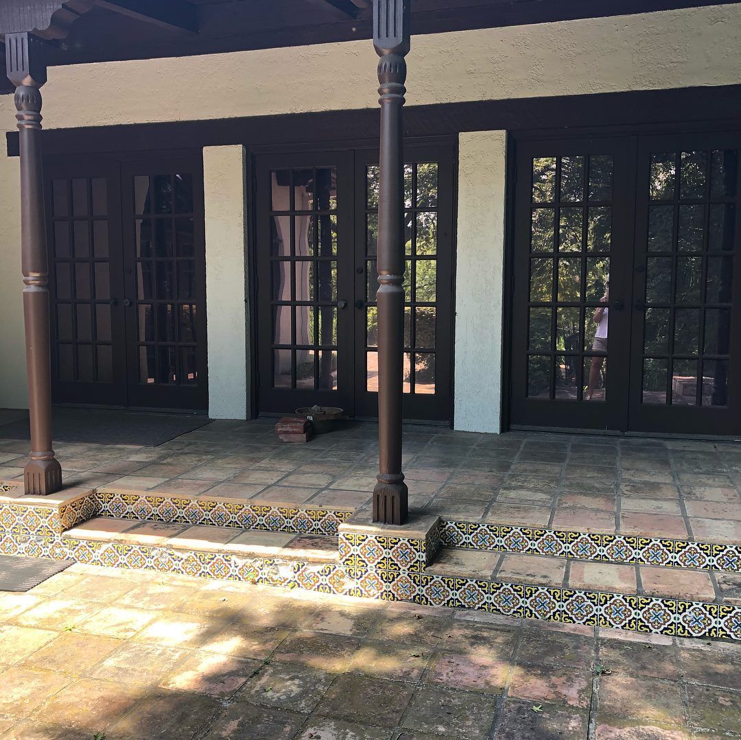 Terrace with tiled steps and dark wooden doors under a veranda.