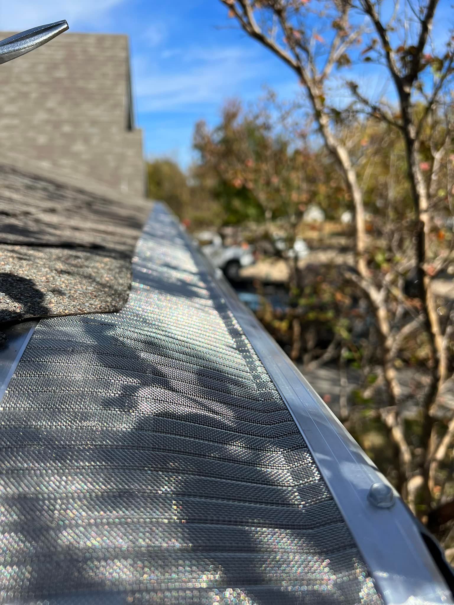 Gutter guard with mesh screen on a roof, preventing debris from entering the gutter.