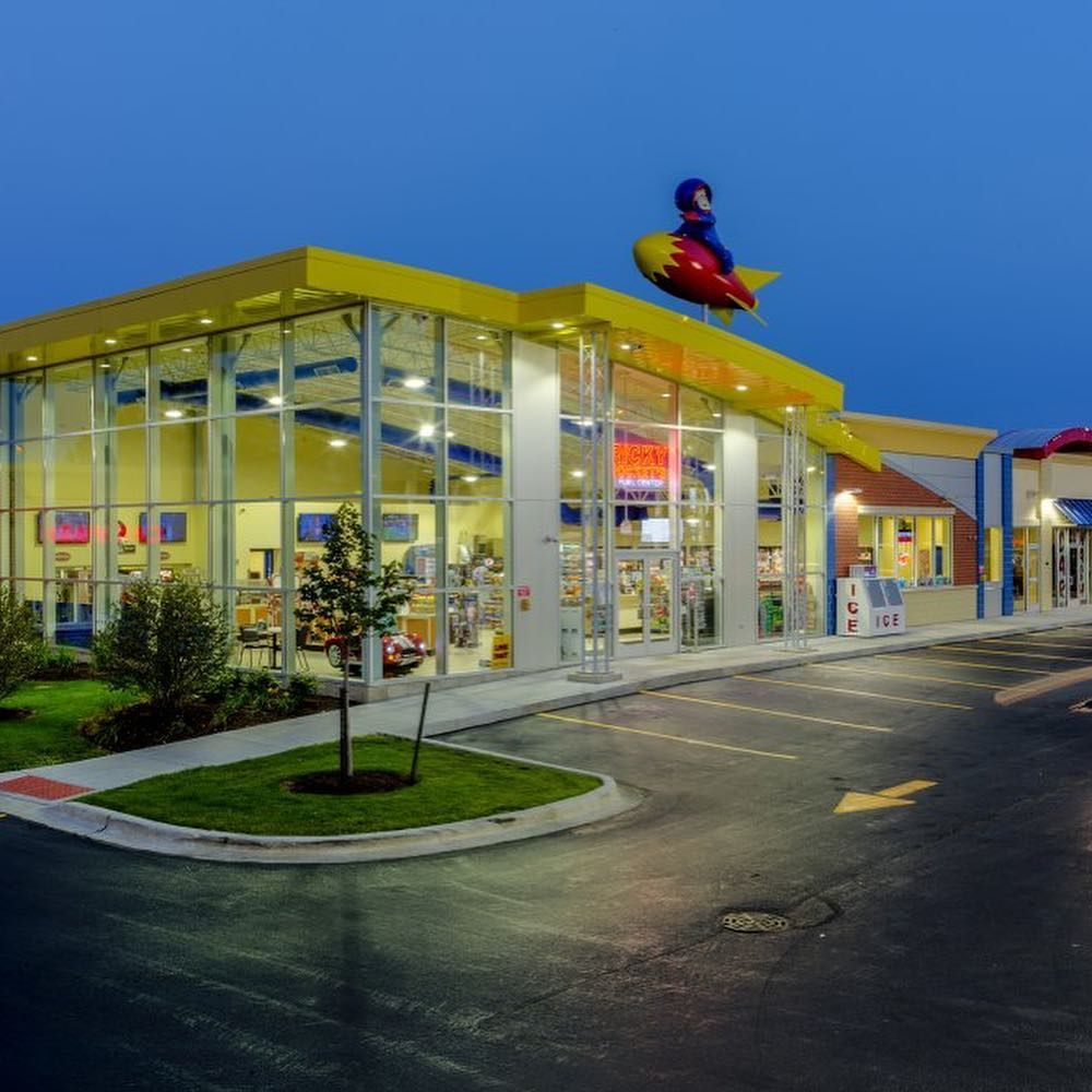Building with yellow trim, glass windows, and a rocket statue on top. A boy rides the rocket.