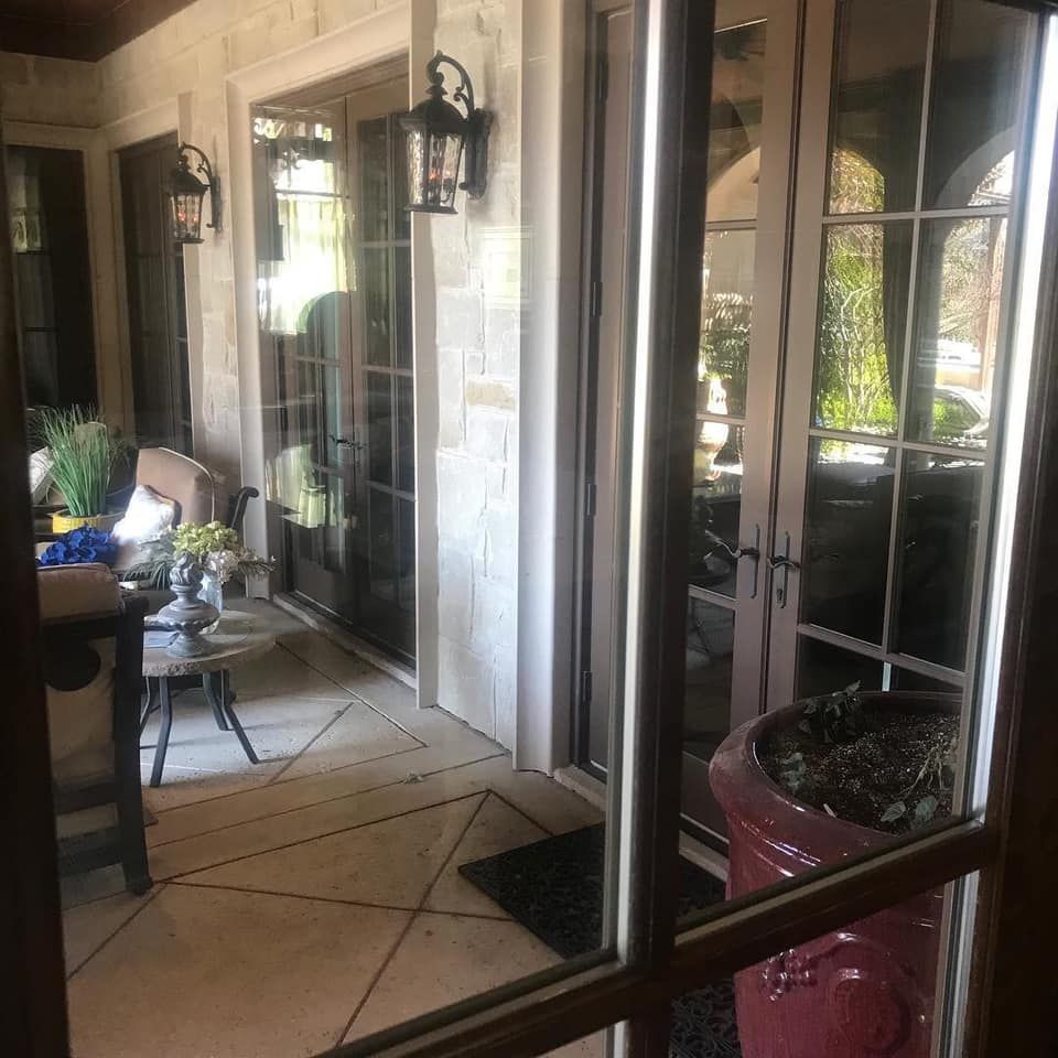 Patio with glass doors, stone walls, black lanterns, and a red planter with plants.