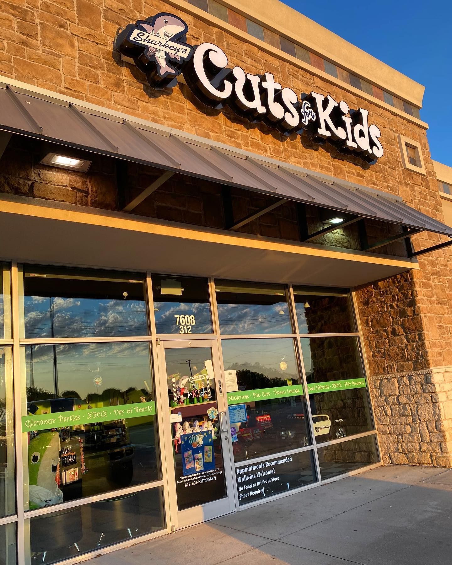 Exterior of a Cuts for Kids salon with glass windows, brick and tan siding.