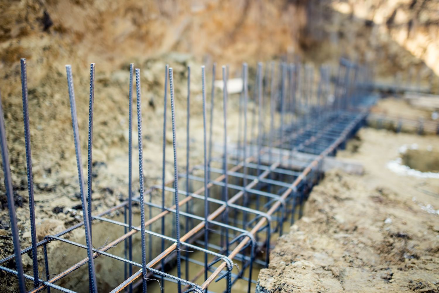Steel rebar cage in an excavated foundation, ready for concrete pouring.