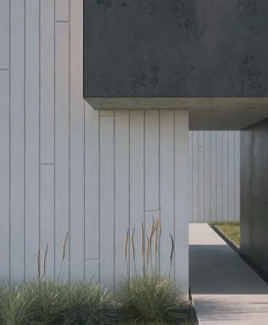Modern building exterior with white vertical paneling, gray concrete accent, and grass.