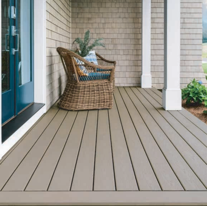 Beige composite deck with wicker chair on a porch, blue door, white columns, and wood siding.