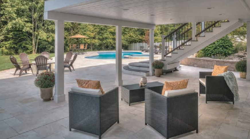 Patio with black wicker chairs, stairs, and pool in a backyard setting.