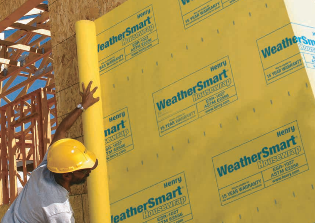Man in yellow hard hat installing yellow WeatherSmart house wrap on a wall.