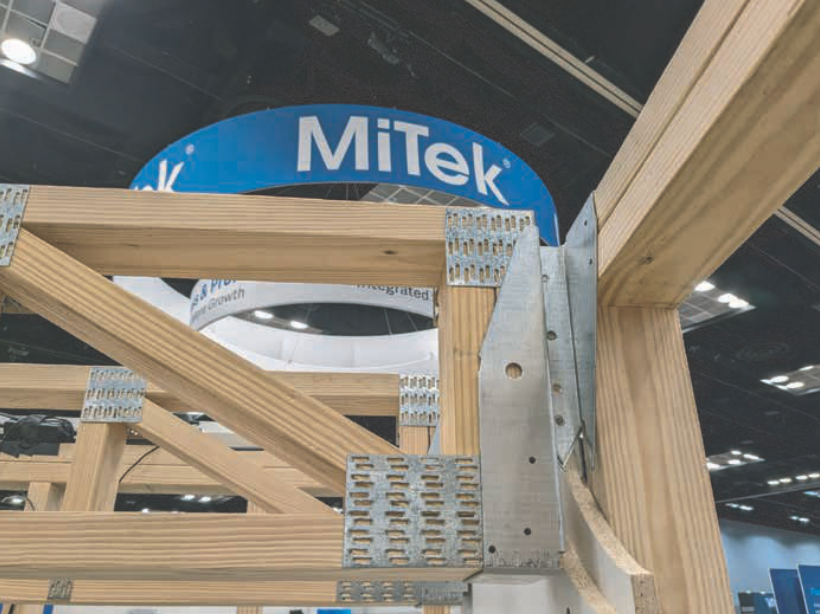MiTek truss hardware connecting wooden beams, showcasing construction techniques at an event.
