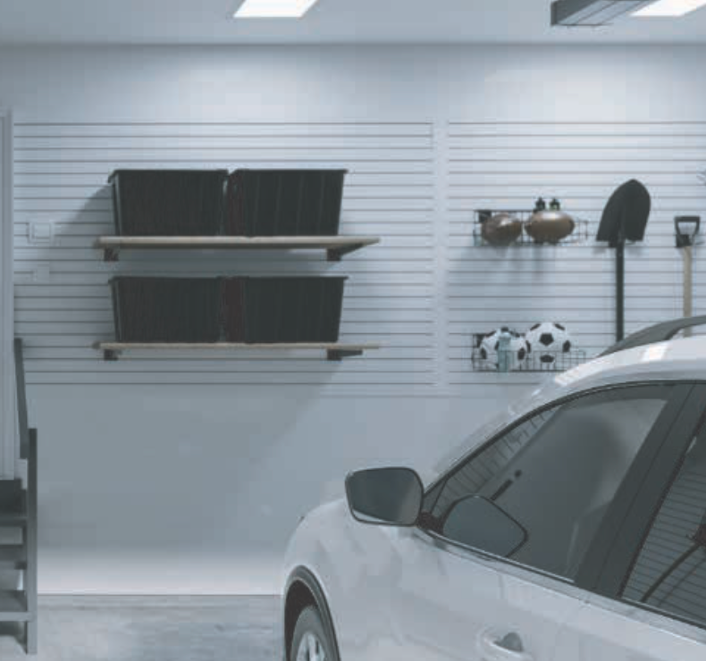 White car parked in a garage with storage shelves holding bins, tools, and sports balls.