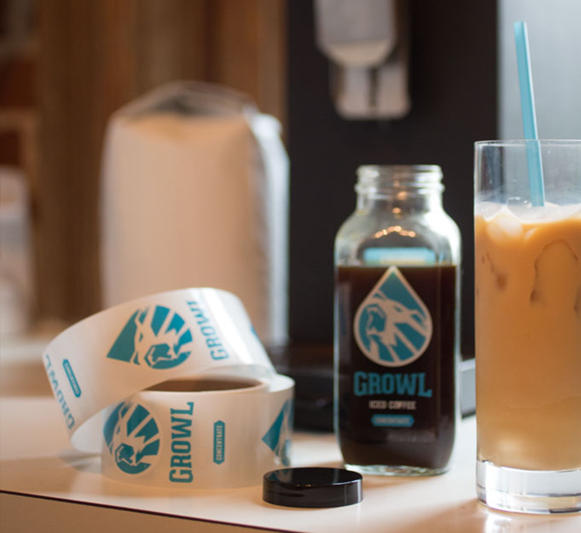 A bottle of coffee sits on a counter next to a glass of coffee