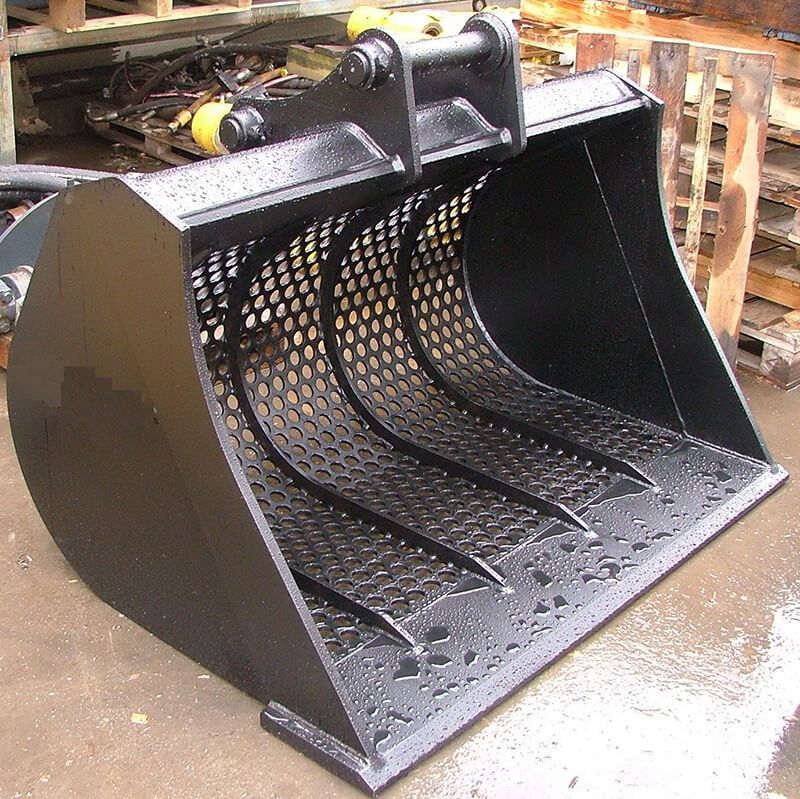 A black bucket with holes in it is sitting on the ground