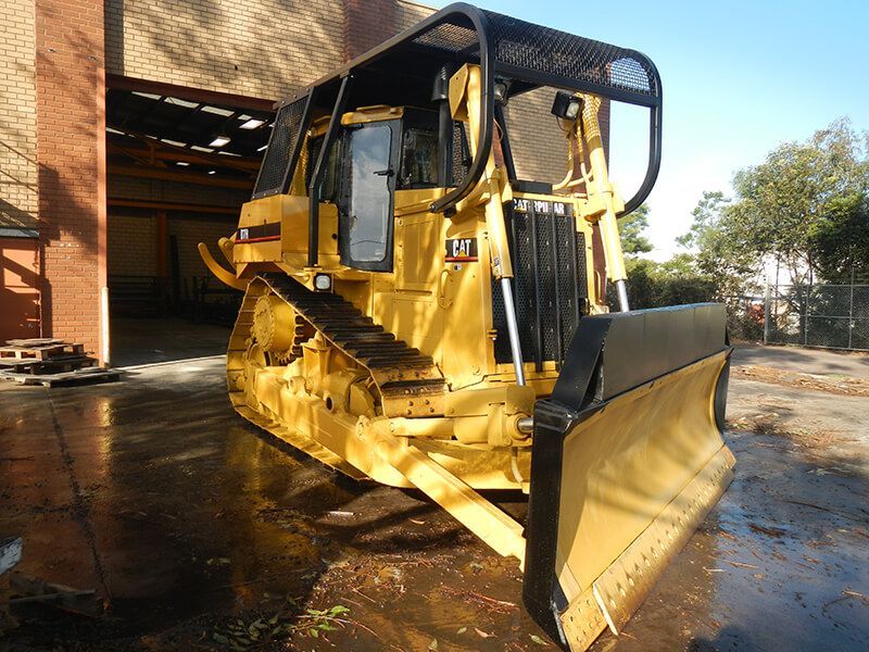A yellow bulldozer is parked in front of a building