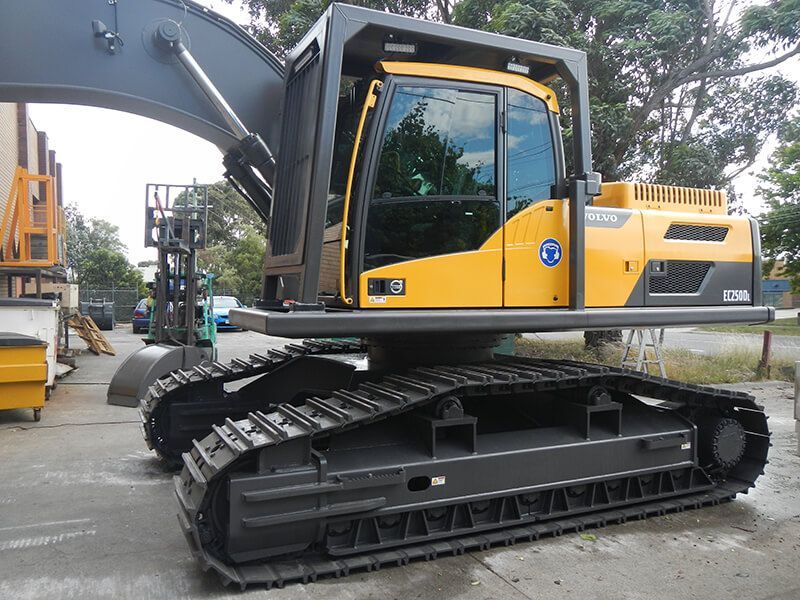 A yellow and black excavator is parked in a parking lot