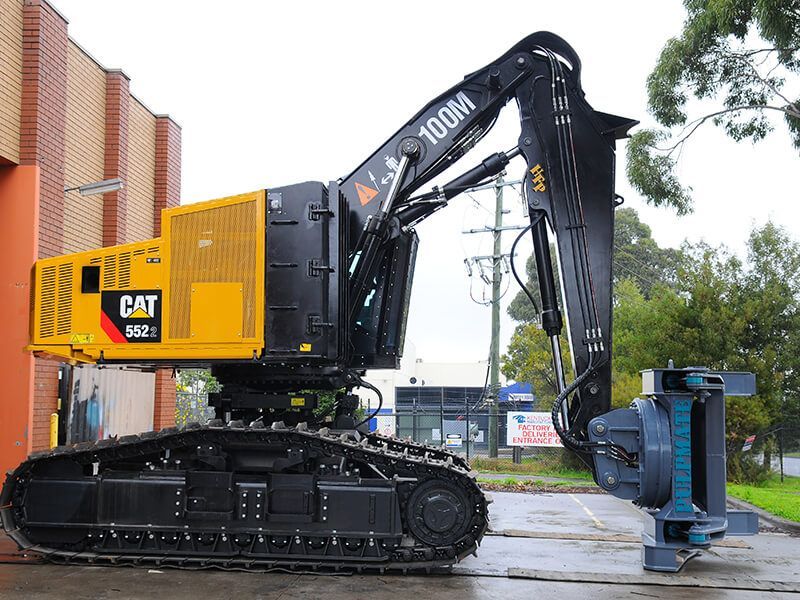 A yellow and black cat excavator is parked in front of a building.