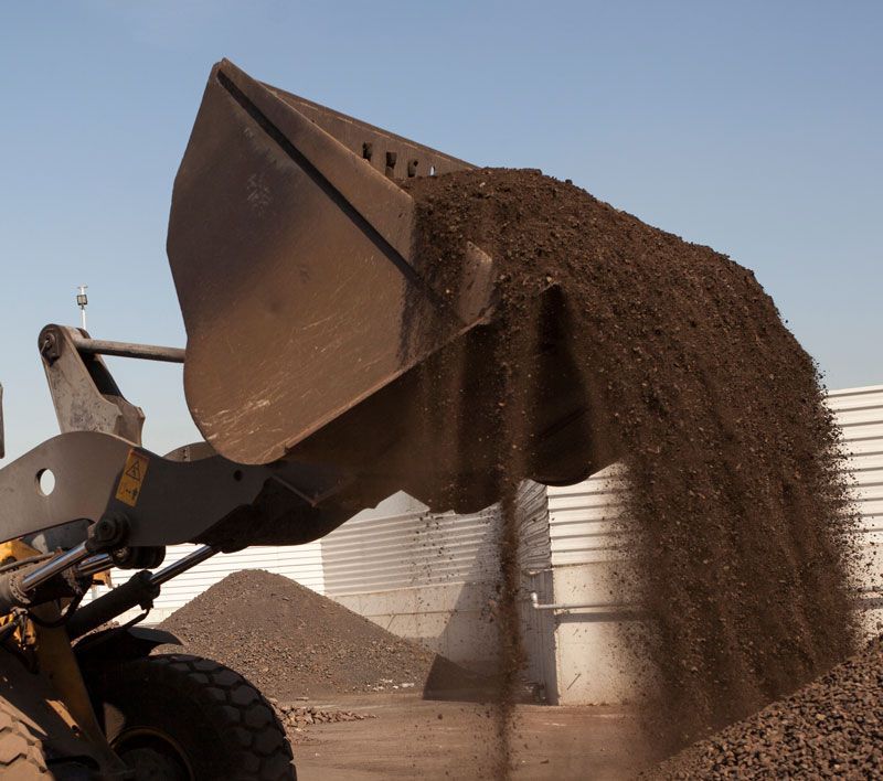A bulldozer is pouring dirt into a pile of gravel