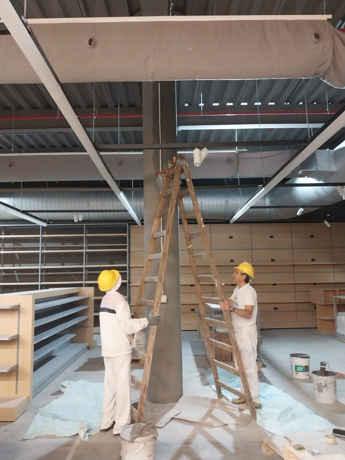 Dos trabajadores de la construcción están pintando un pilar en un edificio.