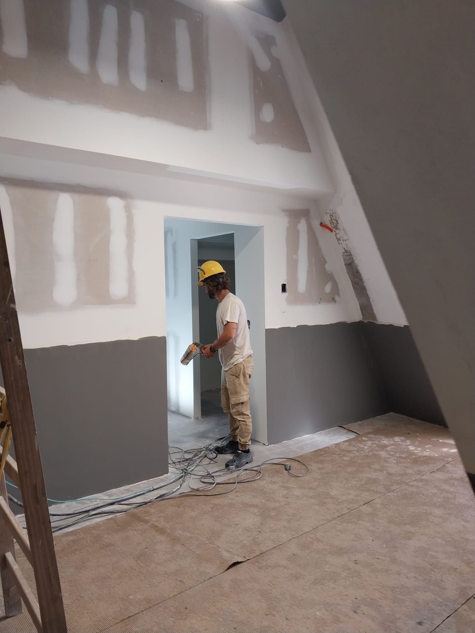 Un hombre está parado en una habitación con una escalera.