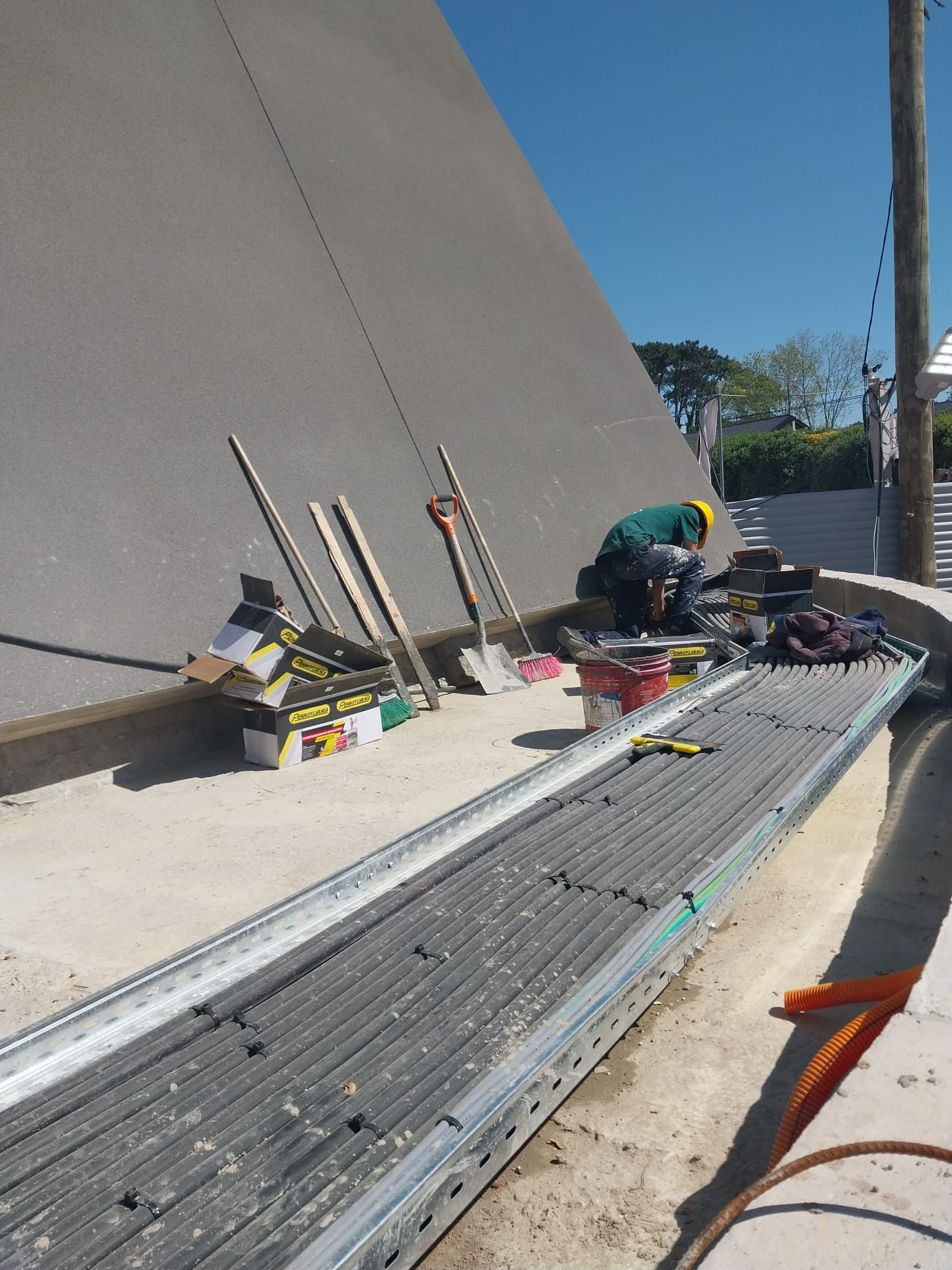Un hombre está trabajando en un techo con herramientas en el suelo.