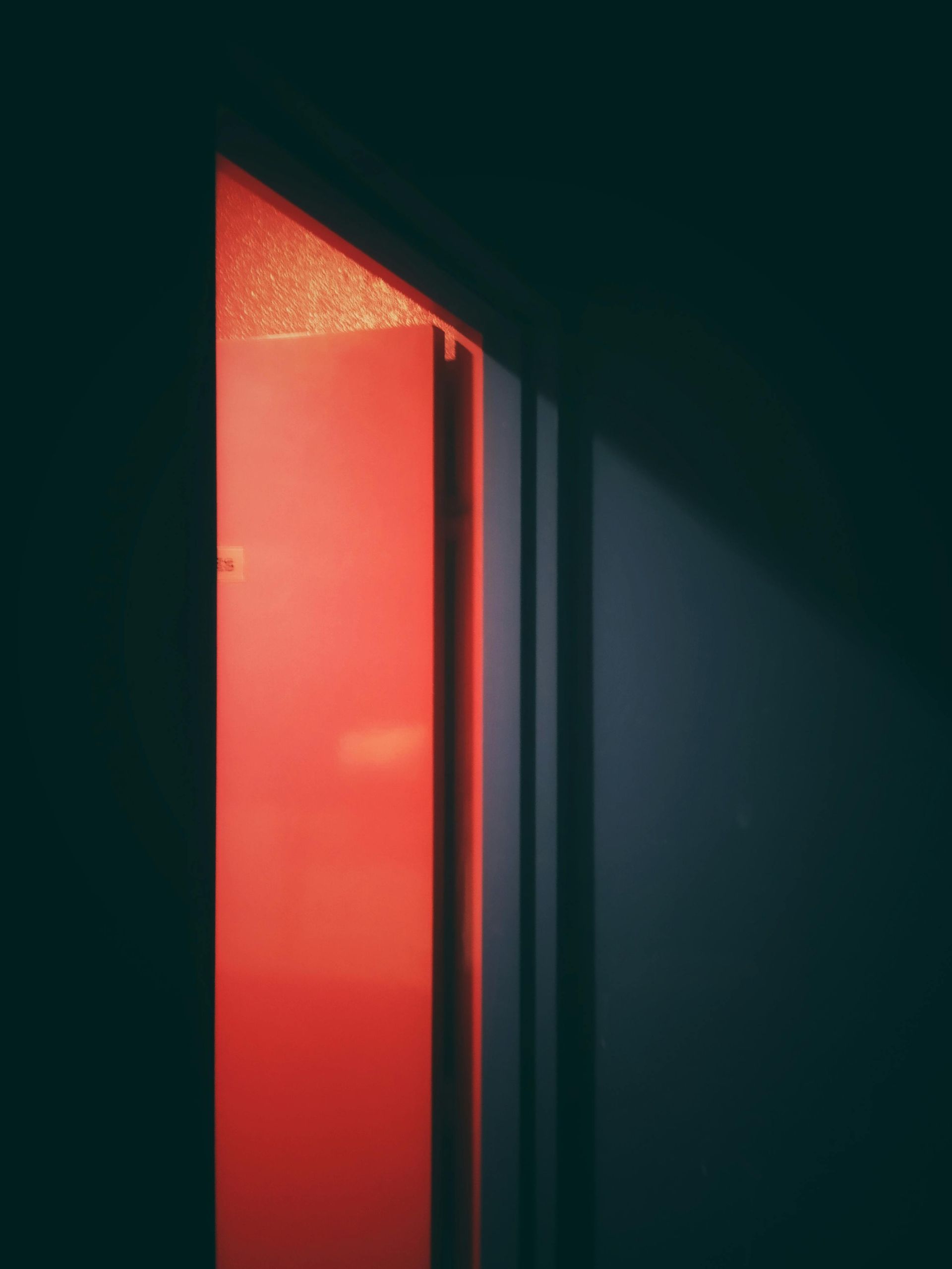 A doorway bathed in red light, creating a stark contrast with the dark surrounding walls.