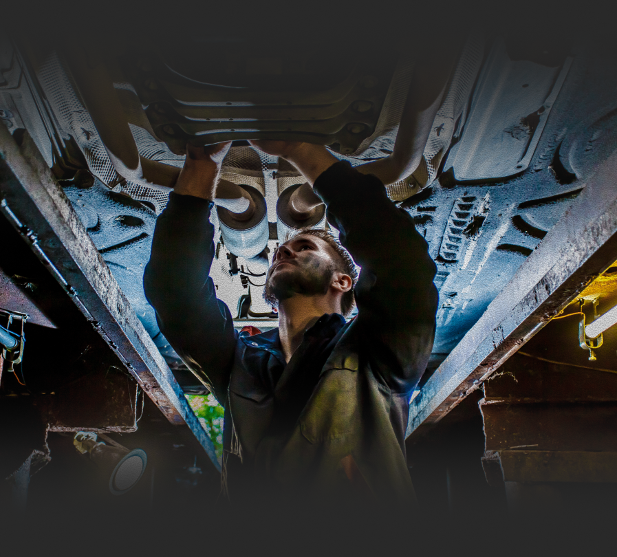 A man is working under a car in a garage. | Barclay Automotive