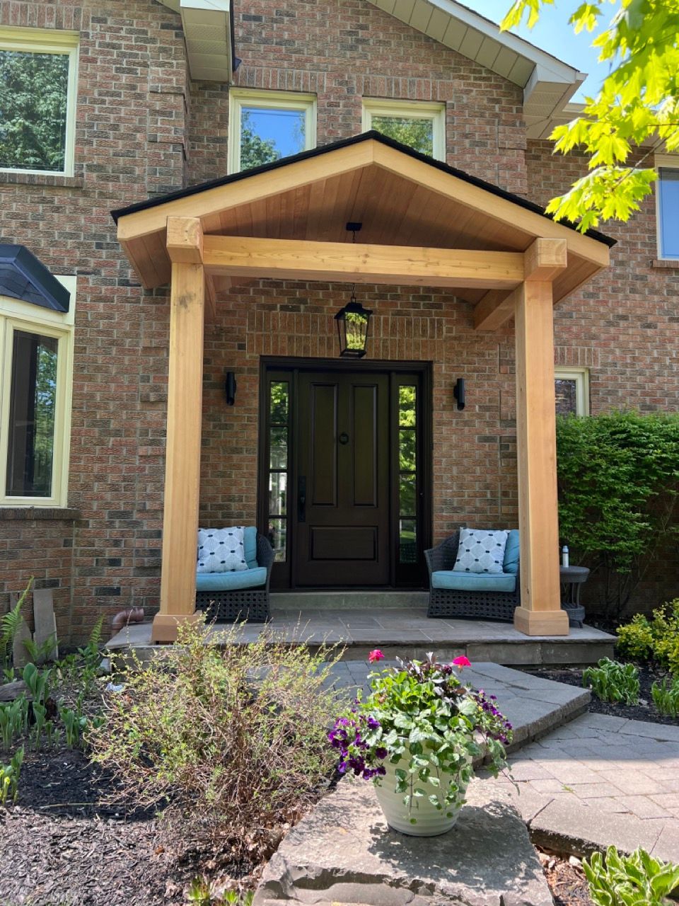 The front porch of a brick house with a wooden porch.