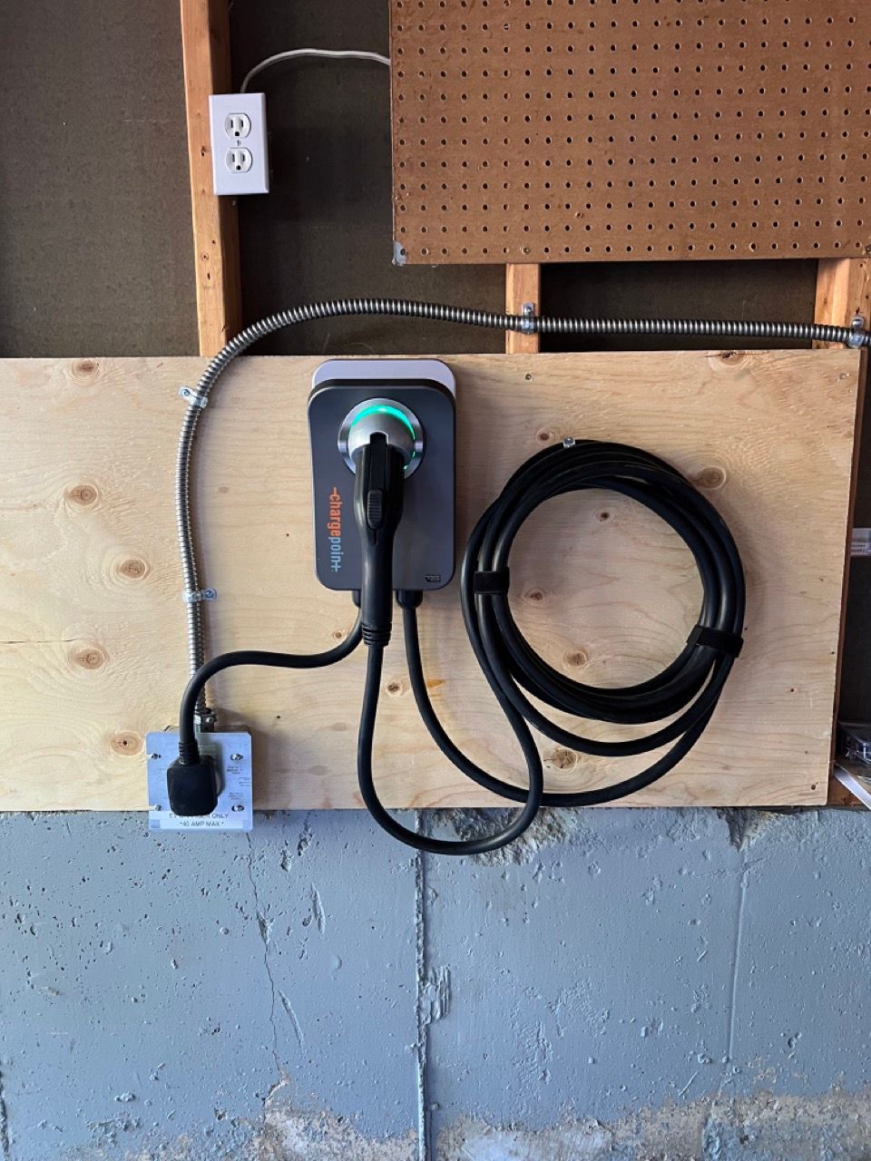 A charger is attached to a wooden board in a garage