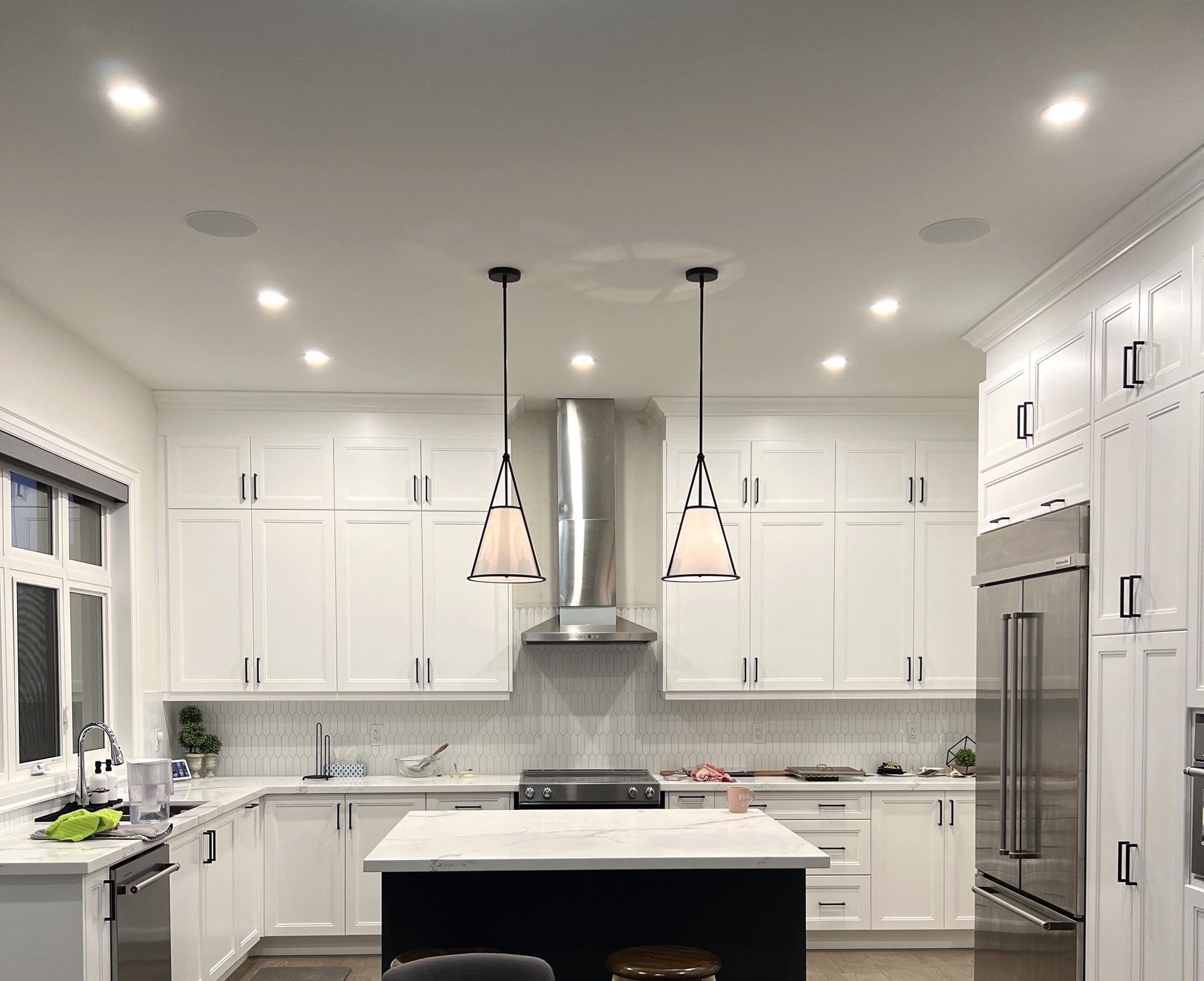 A kitchen with white cabinets , stainless steel appliances , and a large island.