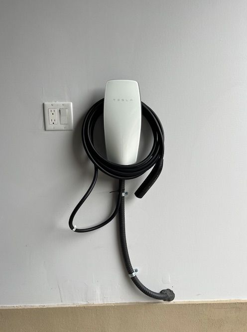 A tesla charging station is attached to a wall.