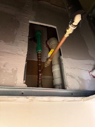 Open ceiling wall cavity with exposed copper pipes, valves, and plumbing lines.