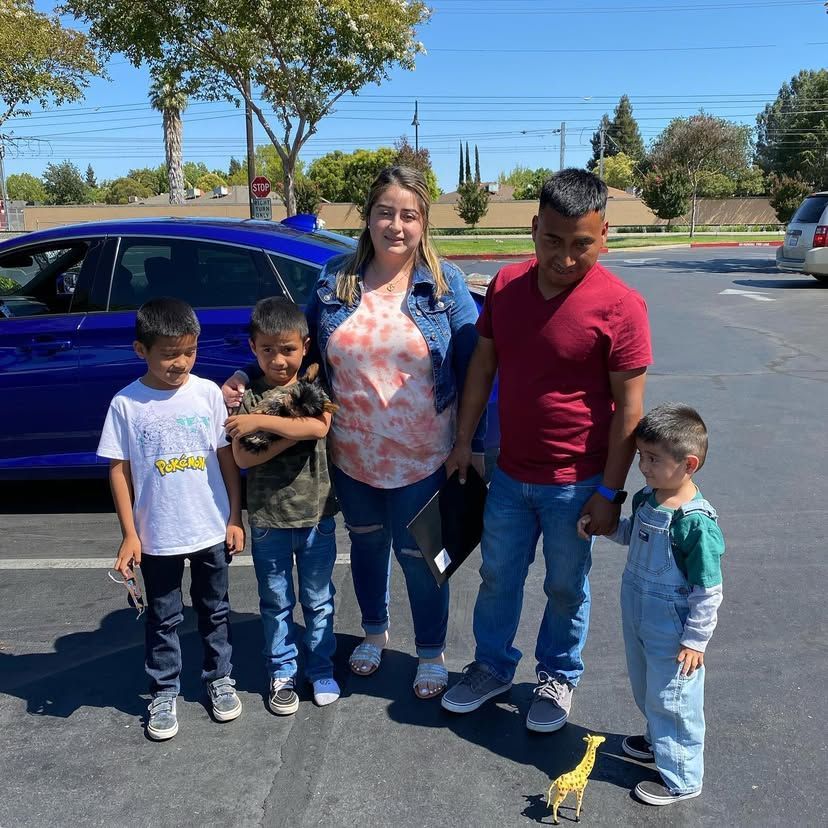 A family posing for a picture in front of a blue car
