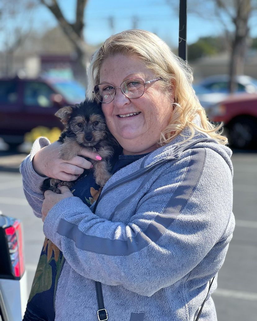 A woman is holding a puppy in her arms in a parking lot.