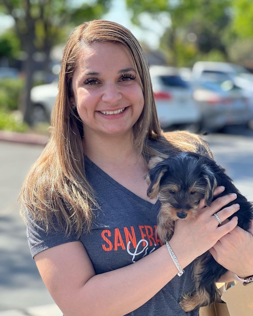 A woman in a san francisco shirt is holding a puppy