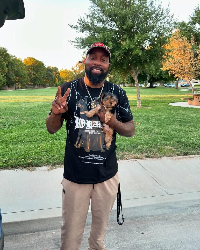 A man with a beard is holding a puppy in a park.