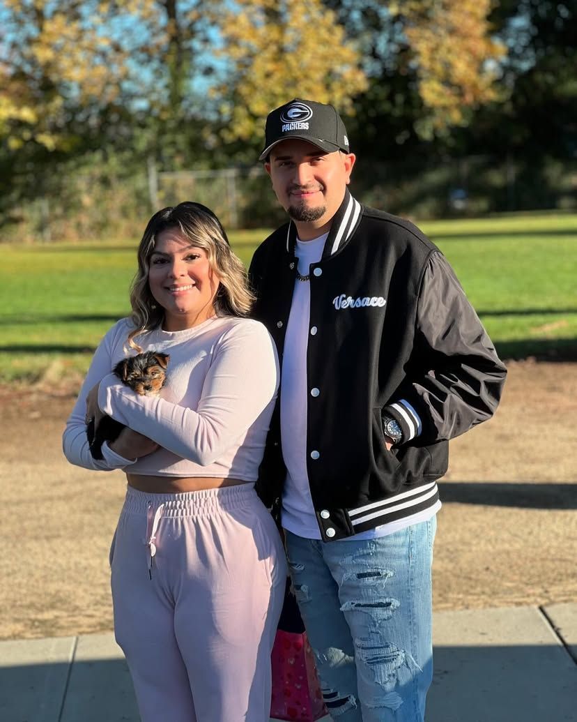 A man and a woman are standing next to each other holding a small dog.