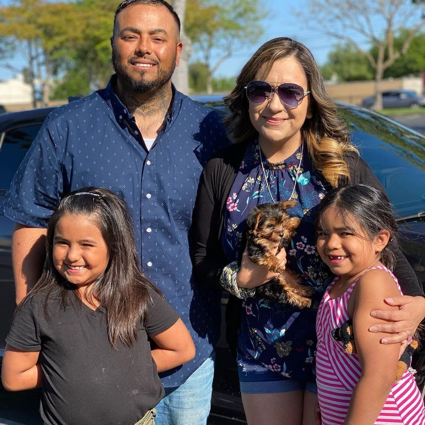 A family posing for a picture in front of a car