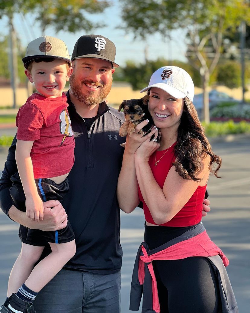 A man and woman are holding a child and a dog.