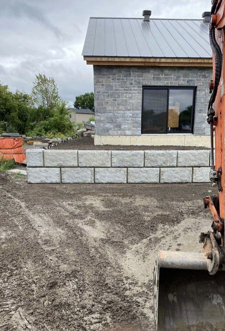 Un grand mur de briques est en construction devant une maison.