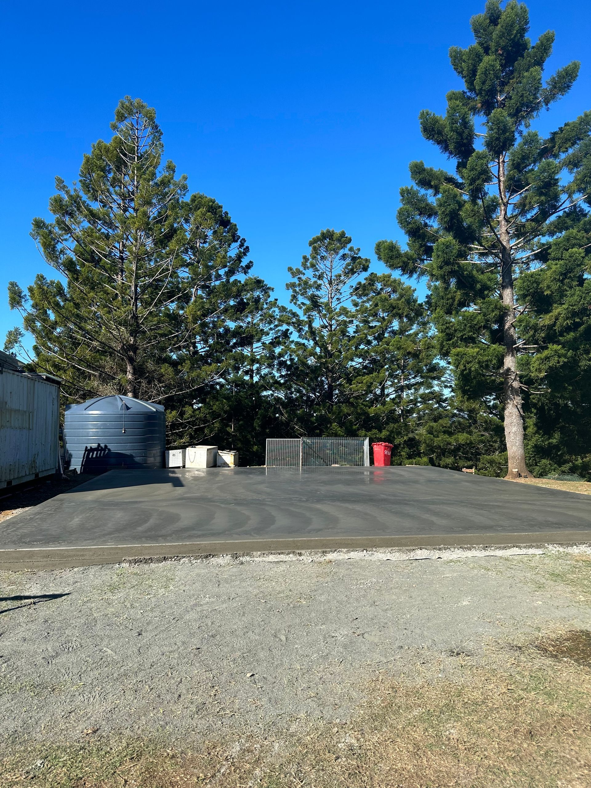 A White Building With A Red Truck Parked In Front Of It — Hinterland Concreting Pty Ltd In Ballina, NSW