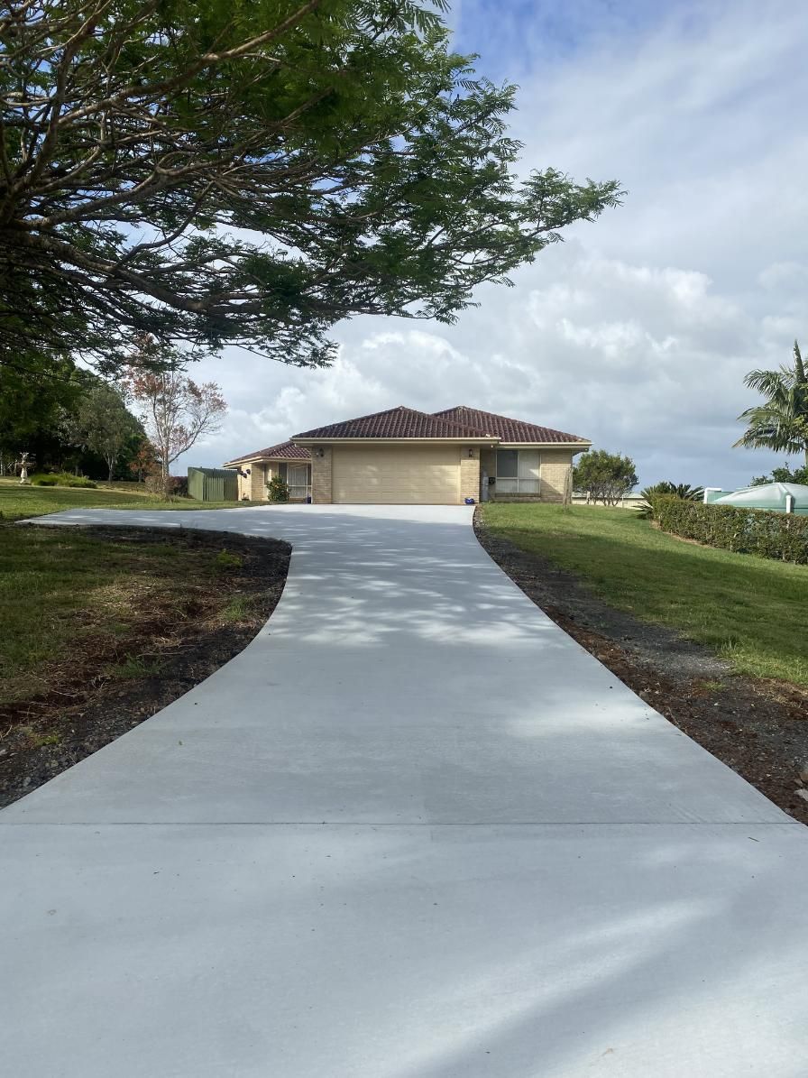 A Concrete Driveway Leading To A House With A Garage — Hinterland Concreting Pty Ltd In Lennox Head, NSW