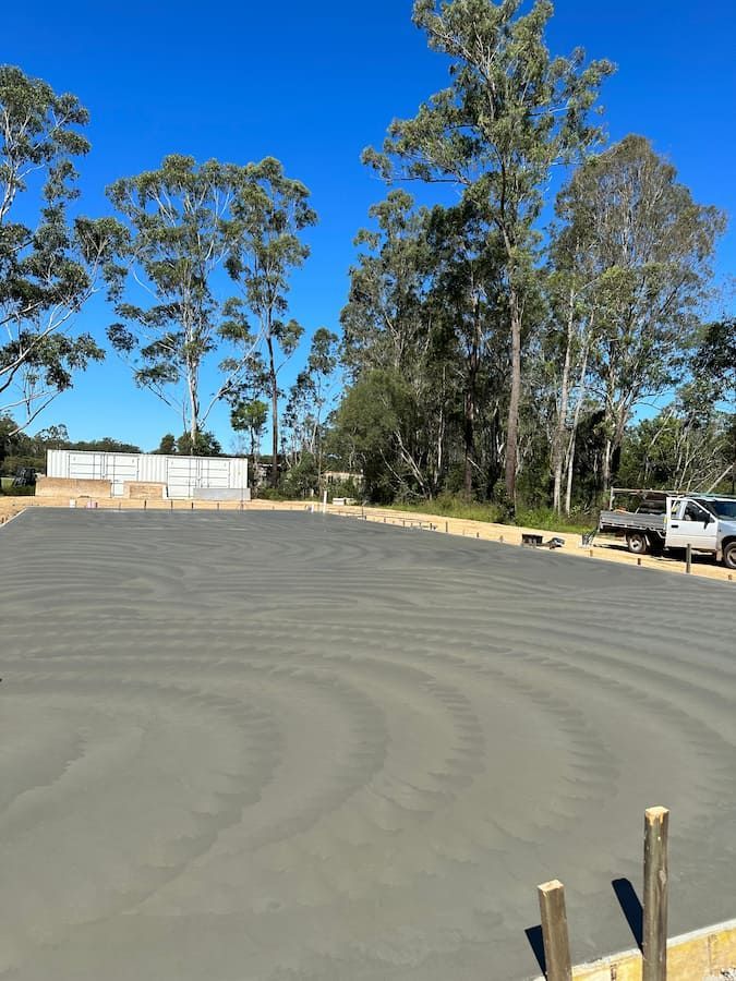 A Concrete Driveway is Being Built With a Lot of Trees in the Background — Hinterland Concreting Pty Ltd In Ballina, NSW