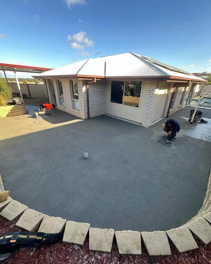 Two People Smooth Fresh Concrete in a Sunny Backyard of a Brick House