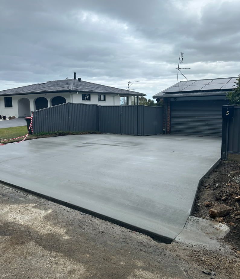 A Concrete Driveway With A Fence And A House In The Background — Hinterland Concreting Pty Ltd In Lennox Head, NSW