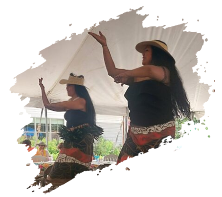 Two women dance under a white tent, wearing black tops, skirts, and hats. They raise their arms gracefully.