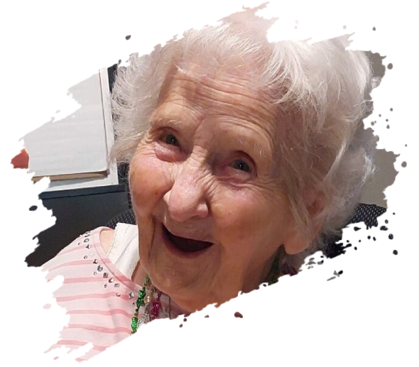 Smiling elderly woman with white hair, wearing a pink and white striped shirt.