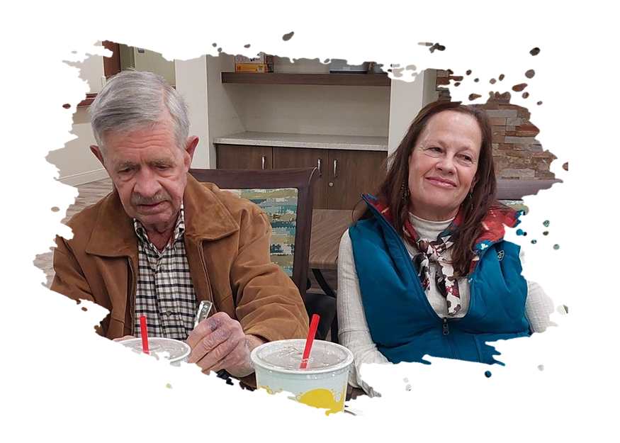 Elderly woman playing cornhole in hallway, throwing red bean bag.