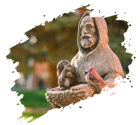 Statue of a bearded man in a hood holding a squirrel and bird; outdoor setting.
