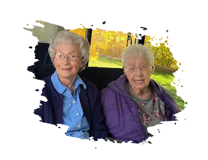 Man in wheelchair talking to a woman, indoors. Man has a beard, hat. Woman smiles, listens.